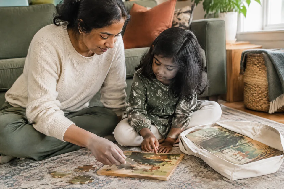 Compact large-piece wooden puzzle and an illustrated picture-only storybook inside a plain open cotton travel pouch.